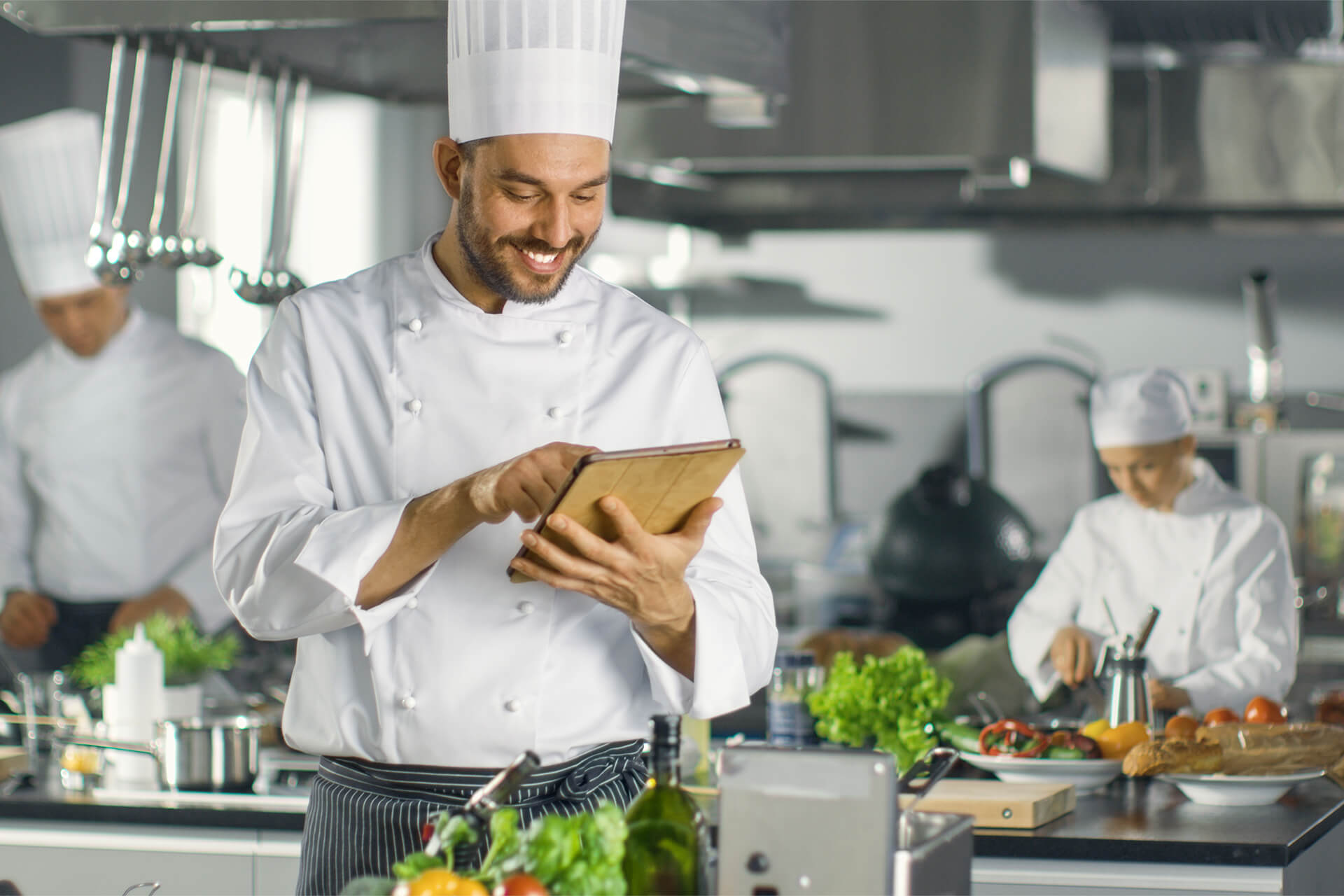 three chiefs working in a busy restaurant kitchen