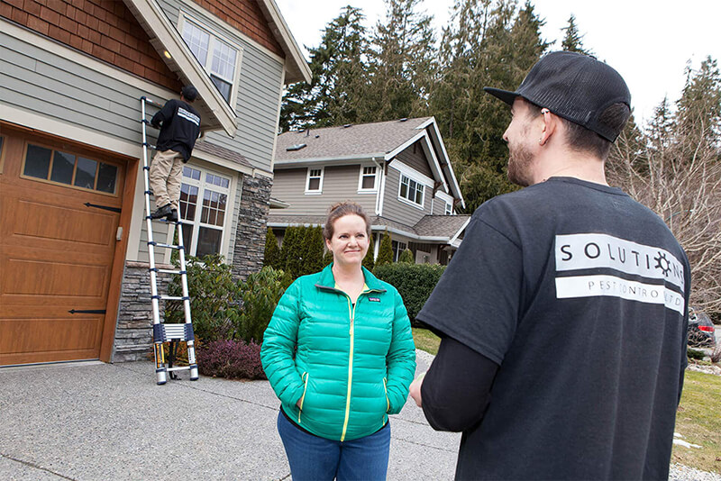 Solutions Pest Control team talking to home owner in front of home