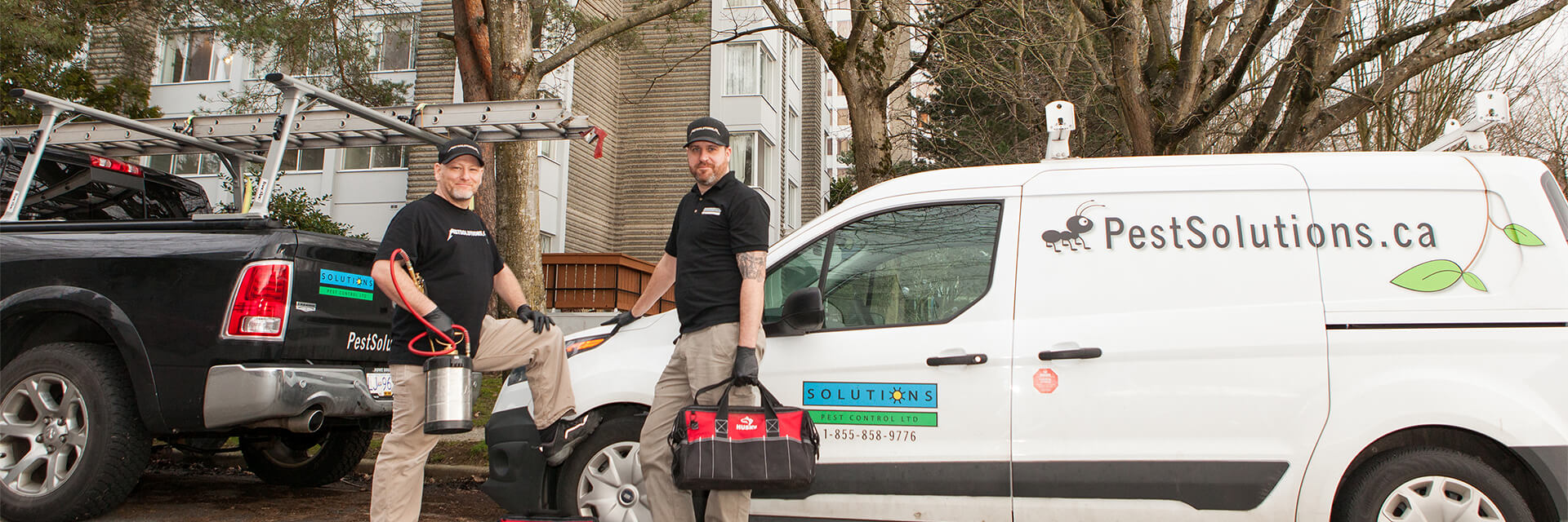 Solutions Pest Control service technicians are ready to help Solutions Pest Control service technicians with their trucks outside large condo building